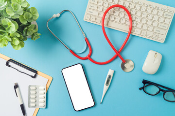 Telemedicine concept with mobile phone, computer keyboard and doctor stethoscope on blue background. Top view, flat lay