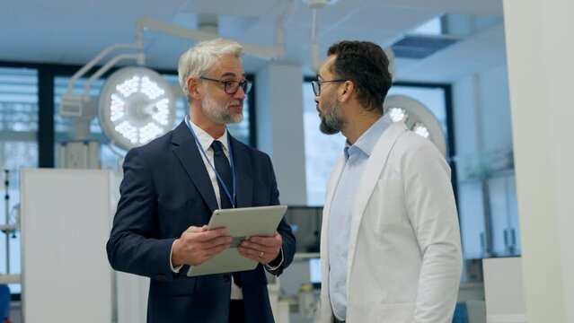 Pharmaceutical sales representative presenting new medication to doctor in medical building, holding box with medication samples.