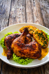 Baked chicken thighs with fried potatoes on wooden table
