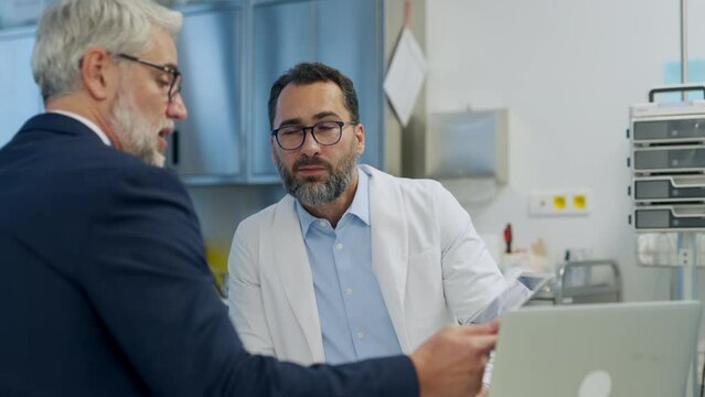 Pharmaceutical sales representative presenting new medication to doctor in medical building, holding box with medication samples.