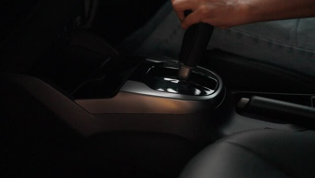 Close-up of a woman's hand adjusting the gear while driving a test drive of a car before purchase in a dealership. car advertising storage