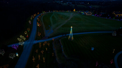 Aerial Nighttime View Of A Large Lit Christmas Tree And Multiple Smaller Trees Decorated With...