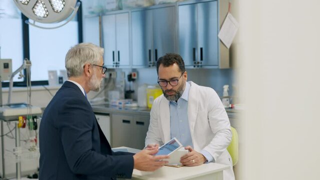 Pharmaceutical sales representative presenting new medication to doctor in medical building, holding box with medication samples.