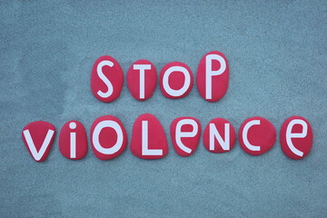 Fototapeta na wymiar Stop violence, pacifist slogan composed with hand painted red colored stone letters over green sand