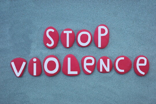 Stop violence, pacifist slogan composed with hand painted red colored stone letters over green sand