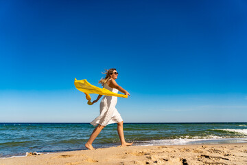Fototapeta na wymiar Beautiful mid adult woman walking, running on sunny beach 