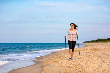 Nordic walking - beautiful woman exercising on beach
