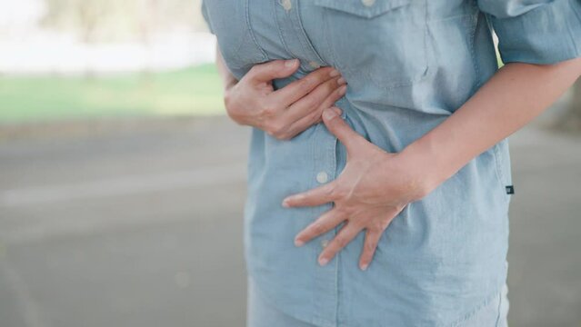 Woman suffering from gastric spasms Abdominal pain outside Stressed young woman massaging her stomach with abdominal pain. Gastritis, stomach pain or menstrual pain, diarrhea.