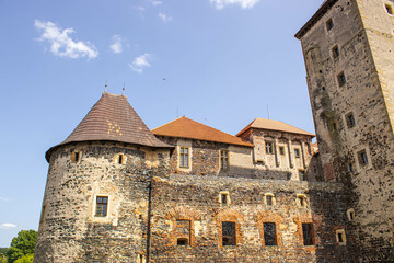 An old castle in the Czech Republic. Picturesque architecture of the Middle Ages. Against the background of the blue sky, the castle looks fabulous.