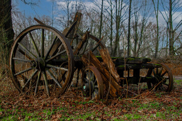 Fototapeta na wymiar An old wooden wagon wheel is sitting in the grass