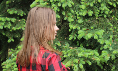 A young beautiful girl in a red plaid shirt and skirt in a park.