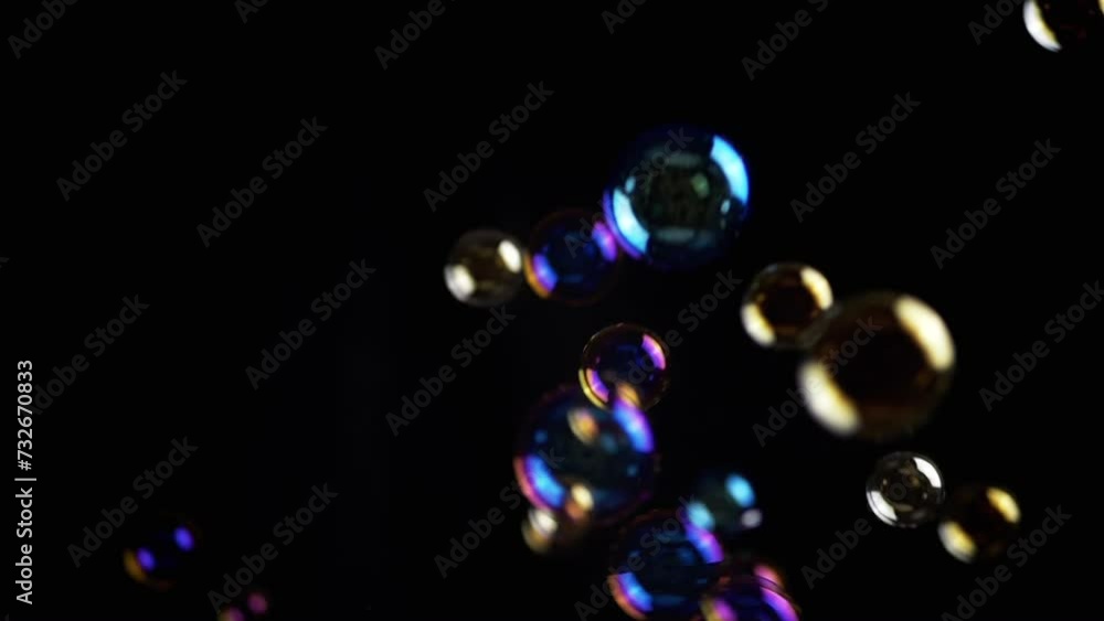 Poster colorful soap bubbles fly in empty space on isolated black background. colorful lights. many rainbow