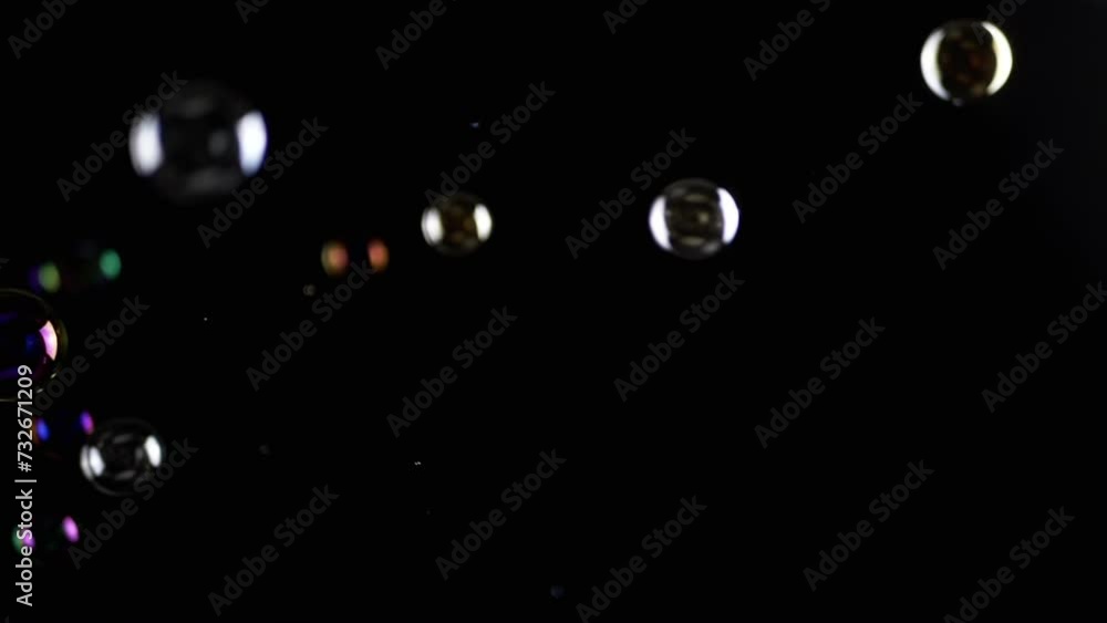 Poster colorful soap bubbles fly in empty space on isolated black background. colorful lights. many rainbow