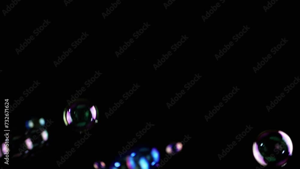 Poster colorful soap bubbles fly in empty space on isolated black background. colorful lights. many rainbow