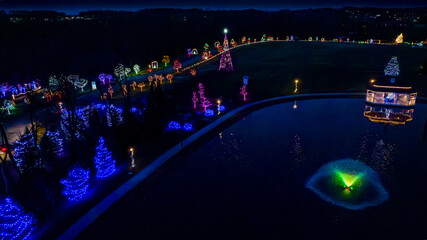 Overhead Nighttime View Of A Serene Pond With A Lit Fountain, Surrounded By A Curved Pathway With...