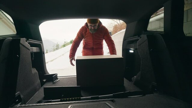 Man buying christmas gifts during winter, bringing box home. Mature man moving to the new house, packing into cardboard box.
