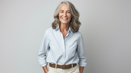 a person with a bright smile, wearing a light blue blouse, standing with hands on hips, exuding confidence and warmth in a professional setting
