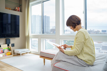 ソファでタブレットするシニア女性