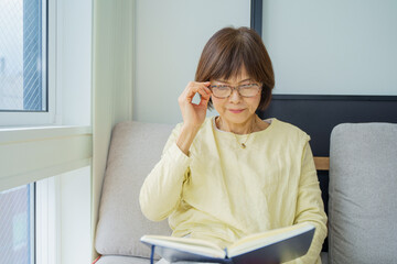 メガネかけて本を読むシニア女性