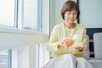 ソファに座って薬をのむシニア女性