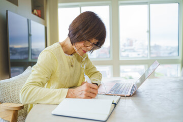 パソコンでリモート会議にでるシニア女性