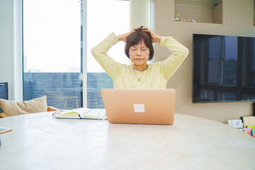 パソコン操作で頭をかかえるシニア女性