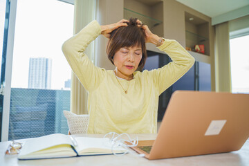 パソコン操作に疲れて頭皮マッサージするシニア女性