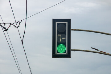 Green traffic light on gray sky background