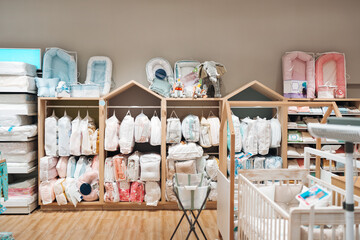 Beautiful baby clothes and bed sheets hanging arranged on rack in a modern store or shop. Shopping...