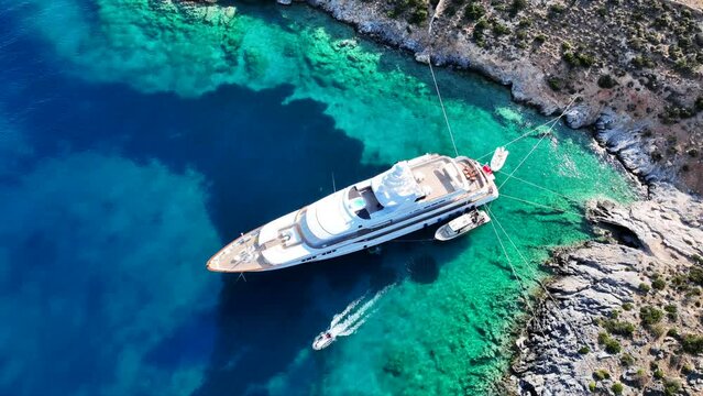 Aerial drone video of luxury yacht anchored in tropical exotic island bay with crystal clear turquoise sea