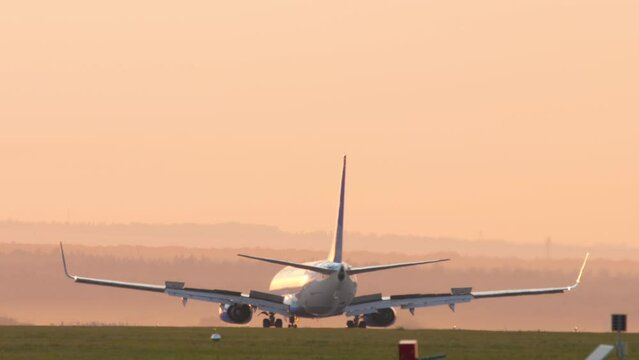 Airplane braking after landing, pink sunset background. Spoilers up. Airliner silhouette on the tarmac