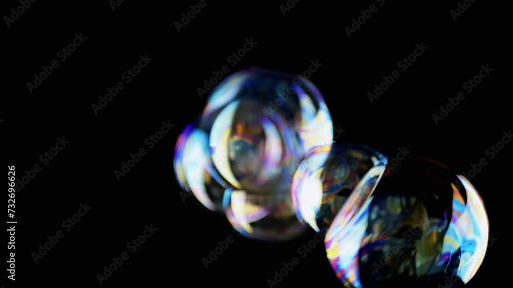 Poster lot of large colorful soap bubbles fly on a black background in empty space. blowing. rotation of st