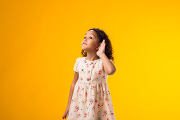 Kid girl eavesdropping, overhearing confidential secret conversation, keeping hand at his ear. Privacy and curiosity concept.