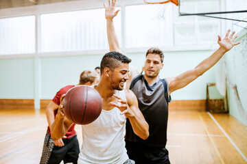 Young men playing basketball in a indoor gym