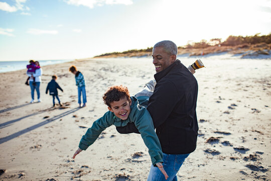 Father and son having fun on the beach with family