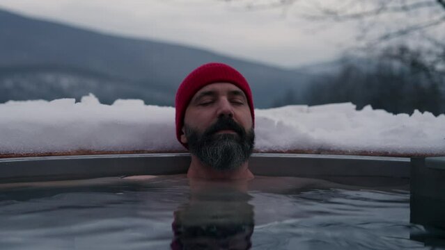 Man doing winterisation outside in small ponds next to his cabin.