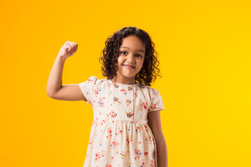 Kid girl showing winner or strength gesture over yellow background. Success, victory and good...