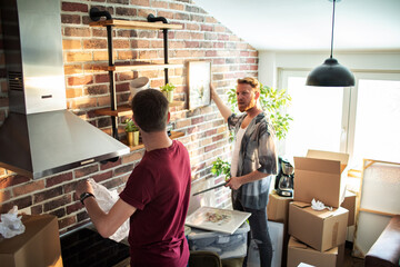 Gay couple hanging picture on wall of new home
