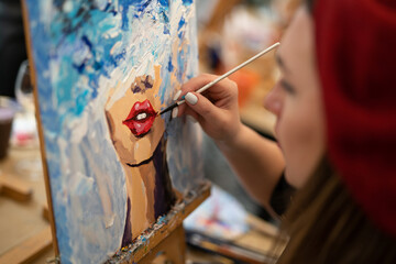 girl artist paints a picture on canvas with oil paints