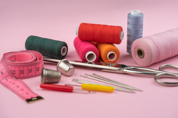 various tailor accessories and tools for tailoring on a pink background