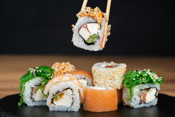 delicious traditional Japanese sushi and rolls on a plate holding chopsticks