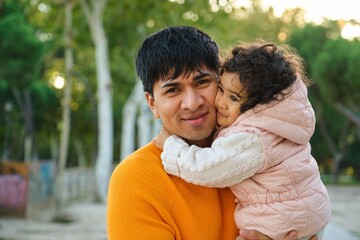 Portrait of happy Ecuadorian one year old daughter hugging her father in a park.