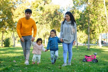 Latin happy family with two children walking together in a park.