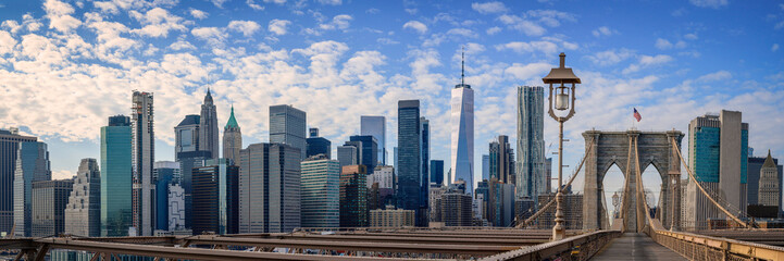 New York City Manhattan Skyline over the Brooklyn Bridge, skyscrapers, the landmark Gothic-Revival massive granite towers, and wooden footpath over the East River in New York