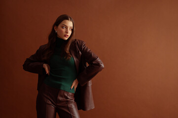 Fashionable confident woman wearing faux leather suit with blazer, pants, green turtleneck, posing...