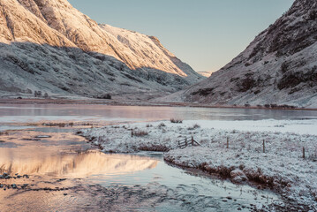 A view of Loch Achtriochtan in Glen Coe, with mountains in the background, on a snowy day in the Scottish highlands