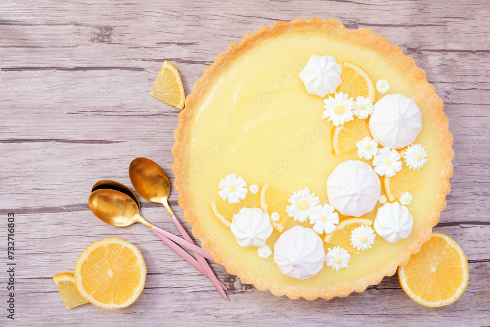 Poster spring lemon tart with white chocolate flowers and meringue. overhead view table scene on a wood bac