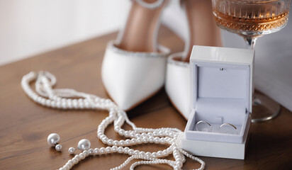 Closeup Bridal accessories with wedding rings. Elegant shoes, perfume, pearl macro photo on wooden...