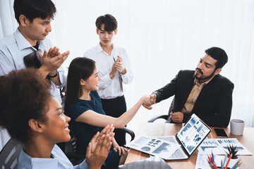 Diverse coworkers celebrate success with handshake and teamwork in corporate workplace....