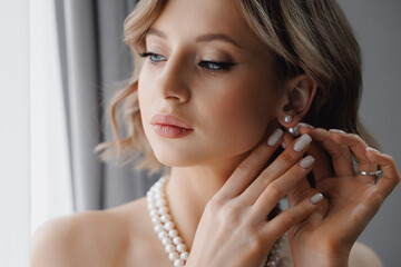 Portrait of happy elegant young woman with white earrings in modern bridal look with classic...